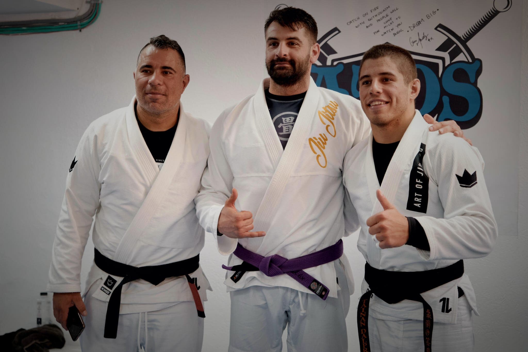 Trei sportivi în kimono alb, unul cu centură neagră
