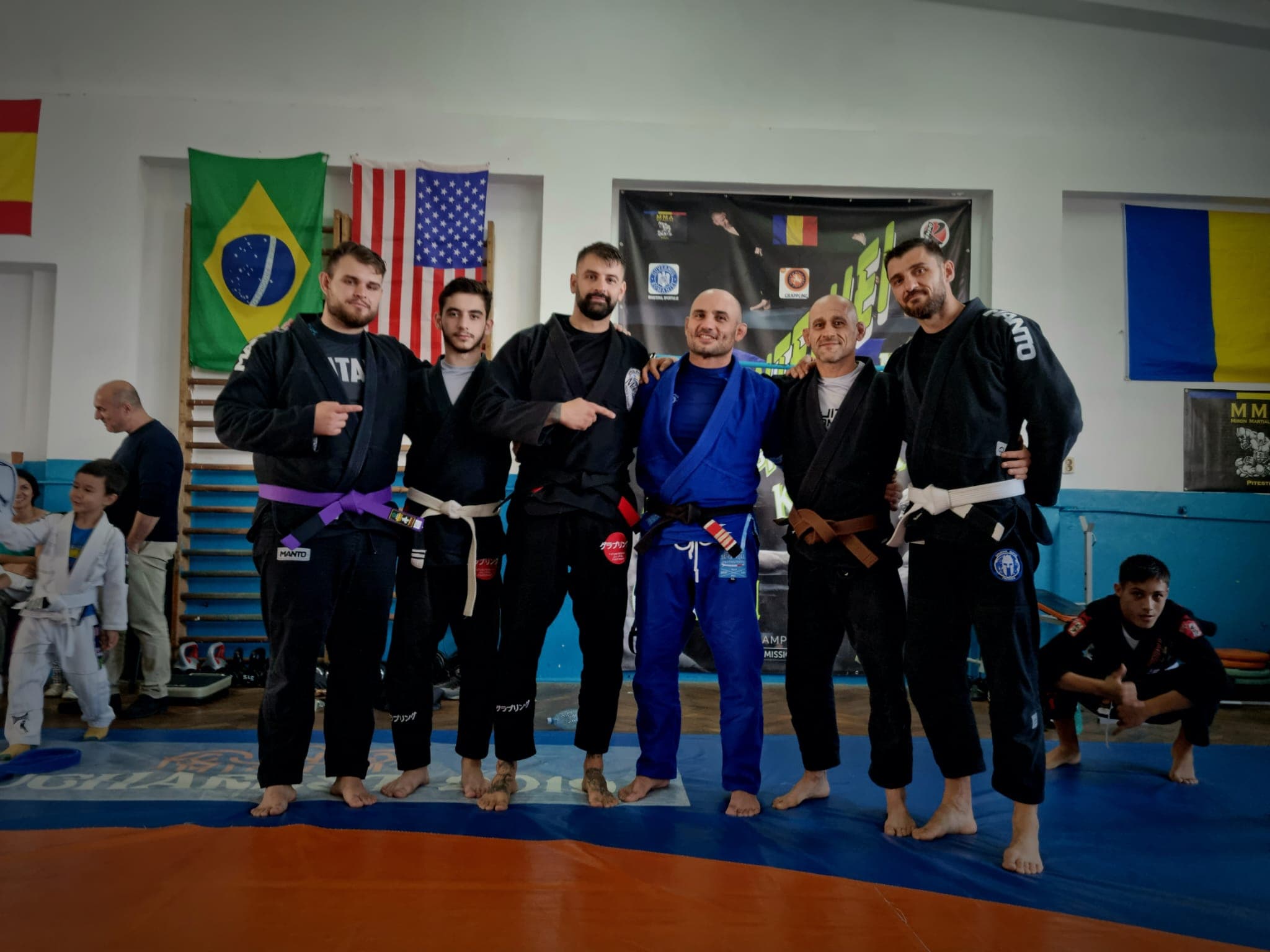 Sportivi aliniați în sală, în fața steagurilor Braziliei, Statelor Unite și României